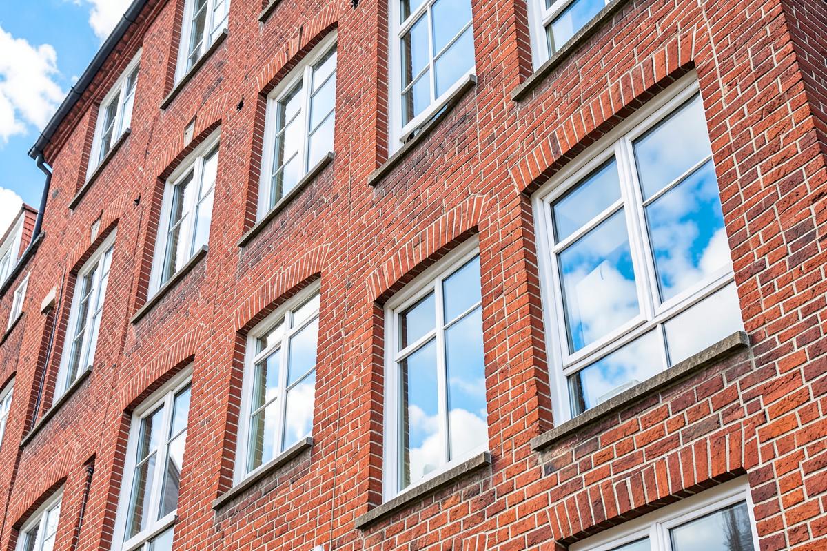 Brick residential building with rows of white-framed windows