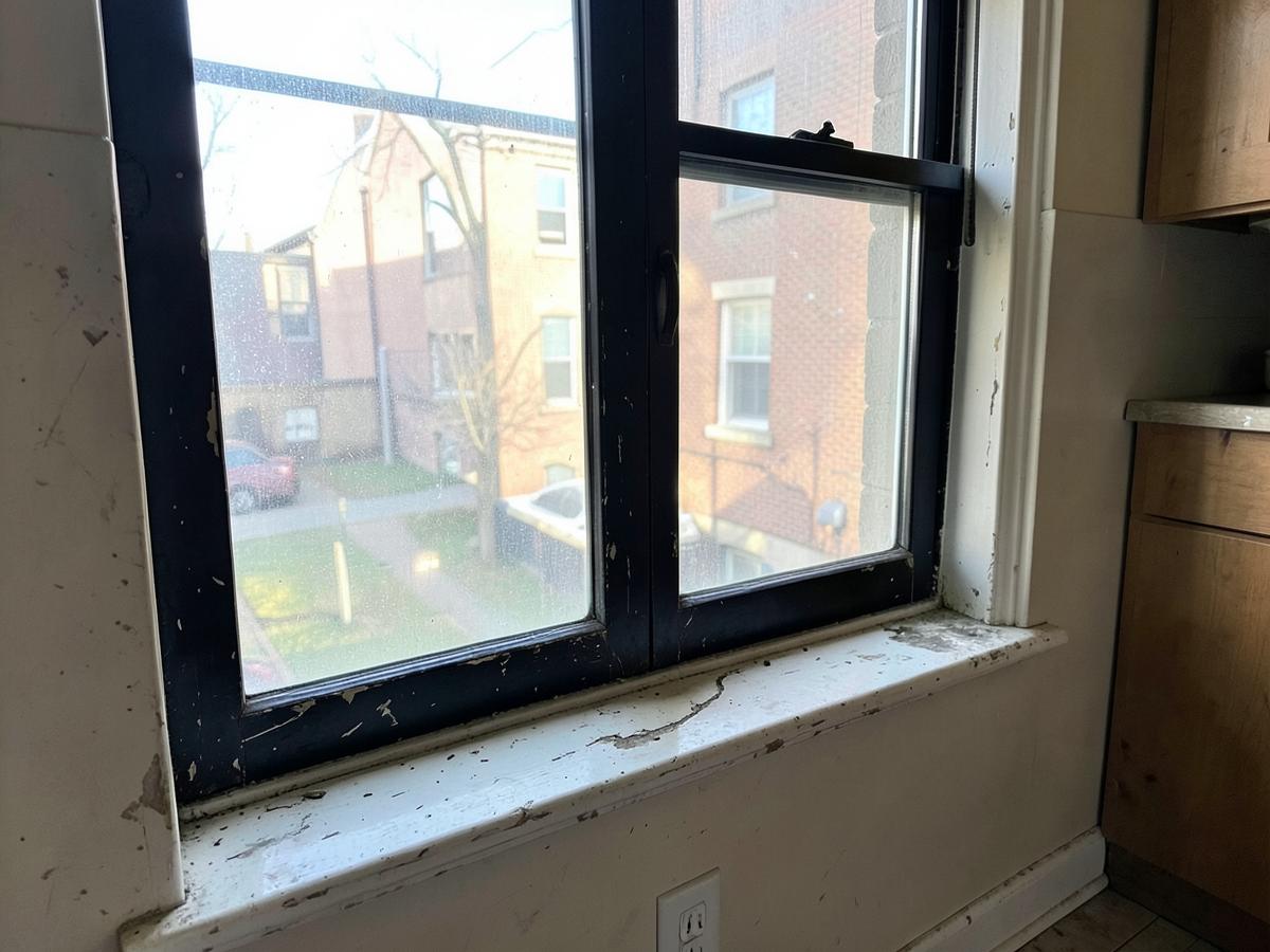 Scratched dark aluminum sliding kitchen window